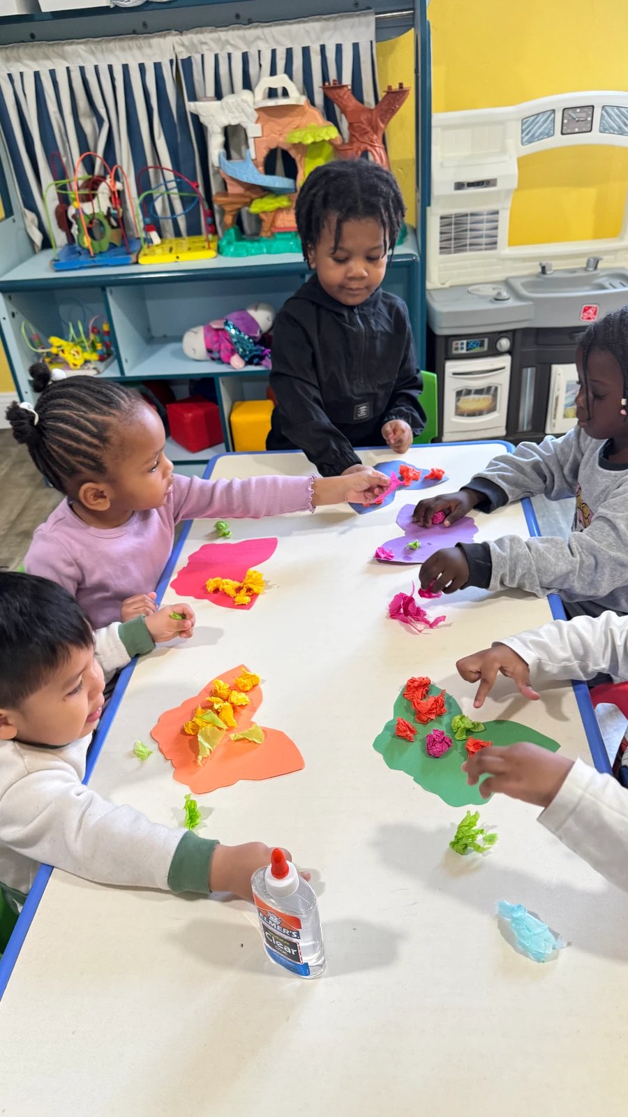 Children working on a tissue-paper craft activity at the table