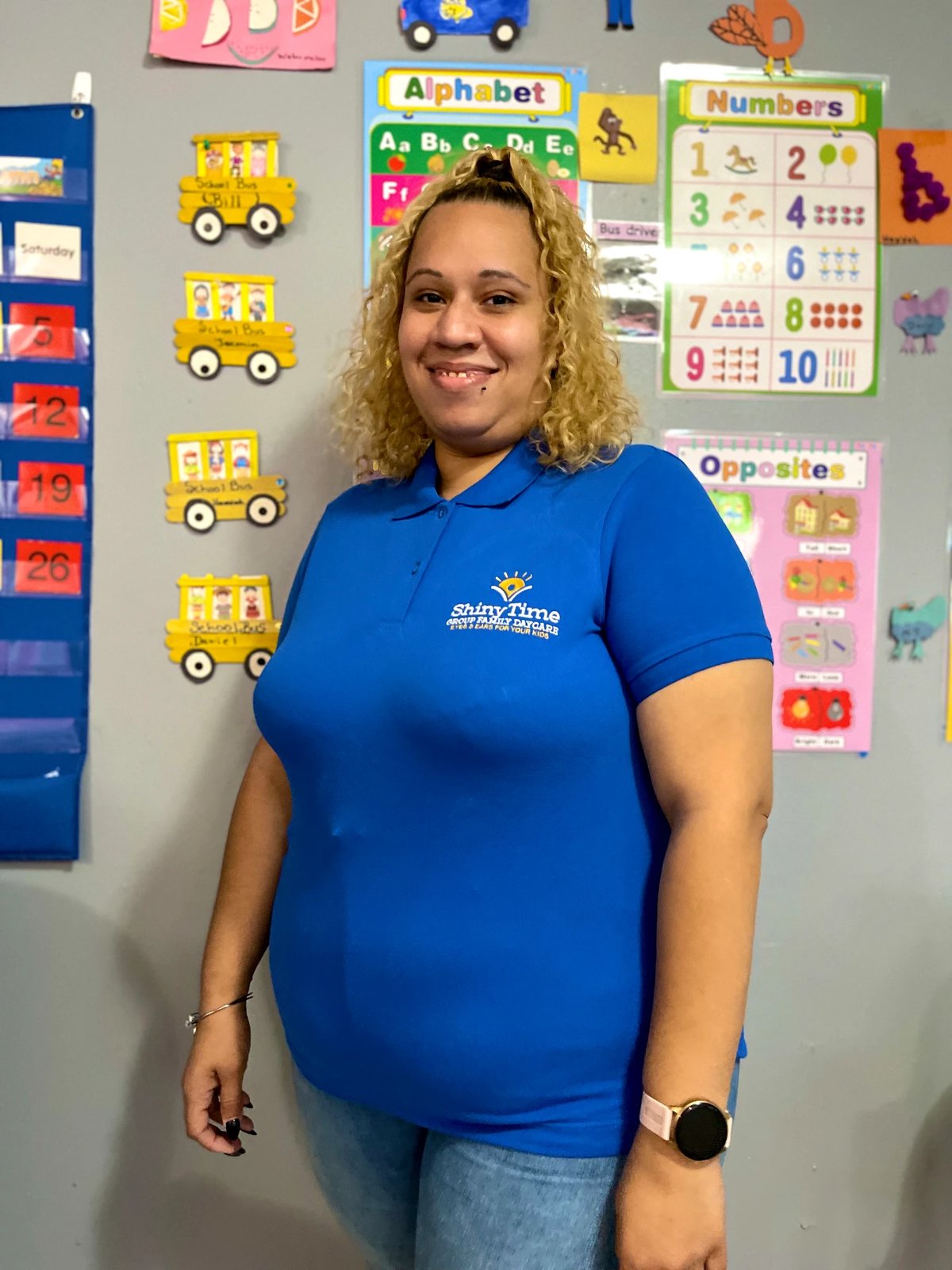 Jasmine smiling in front of the classroom display wall