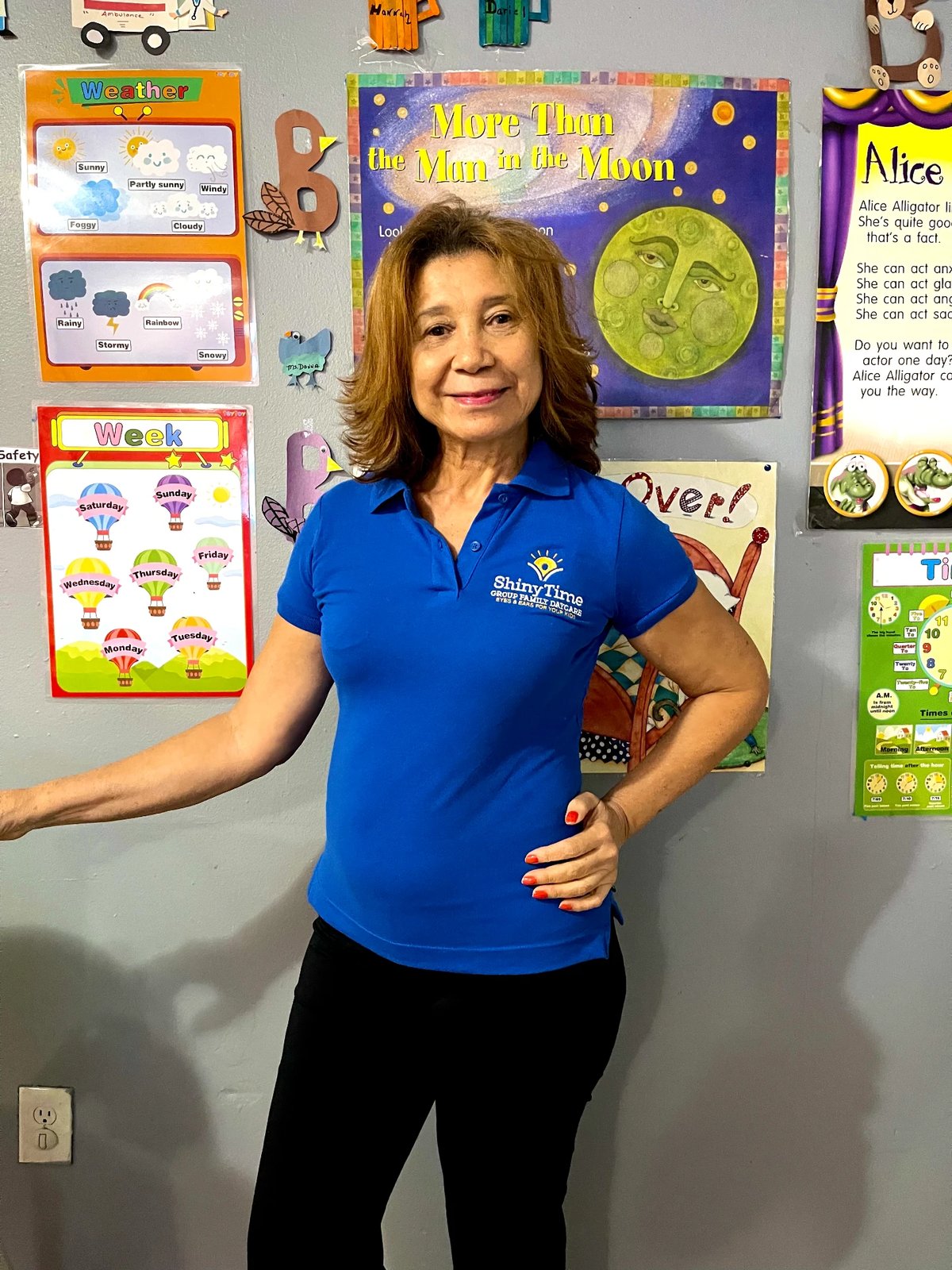 Selenia, smiling in front of the classroom display wall