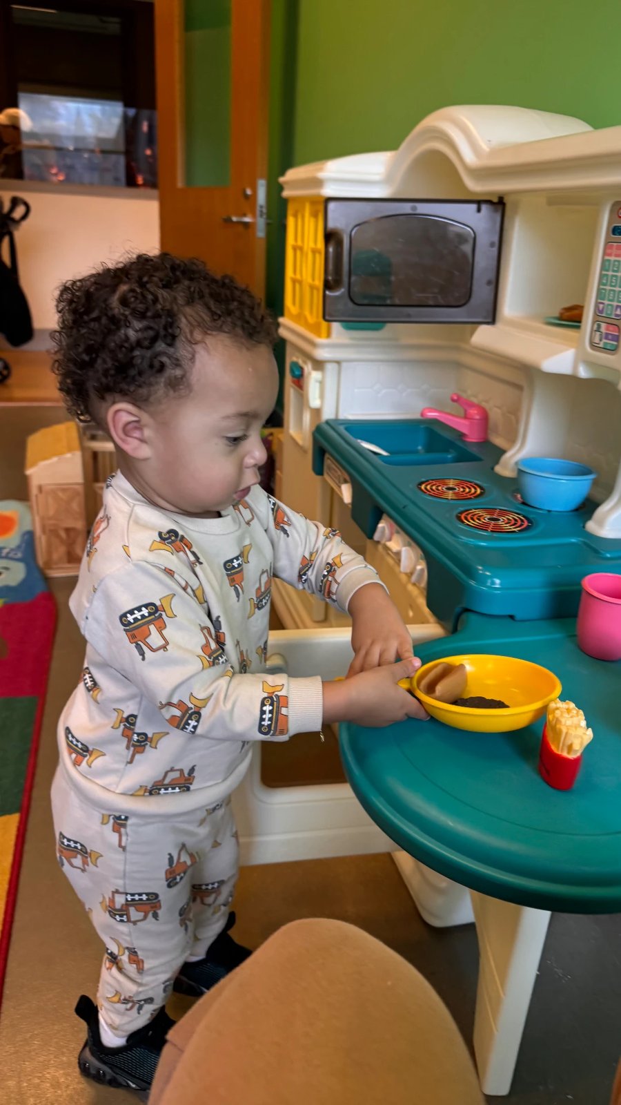 A toddler cooking pretend breakfast at the play kitchen